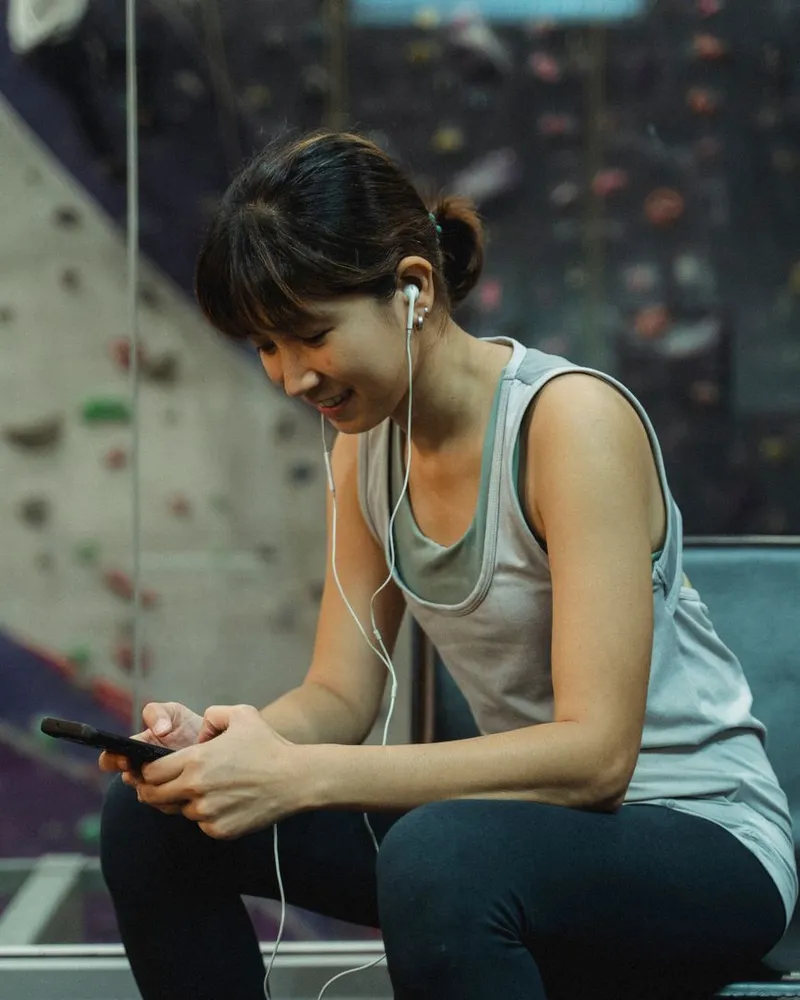 Mulher sentada na academia montando o treino no celular