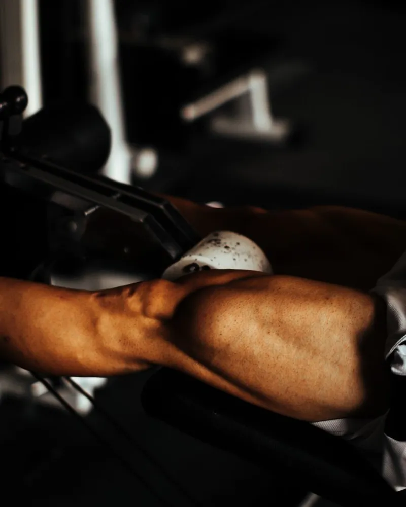Pernas fazendo o movimento na mesa flexora da academia