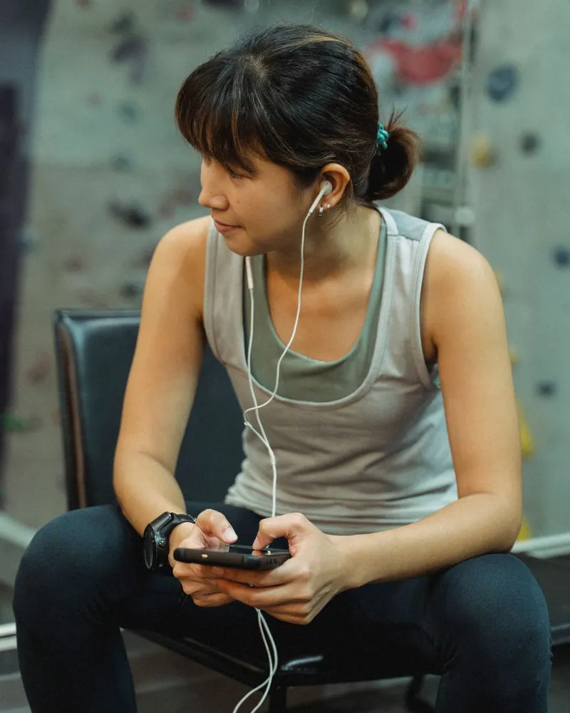 Mulher sentada na academia conferindo o celular entre um exercício e outro