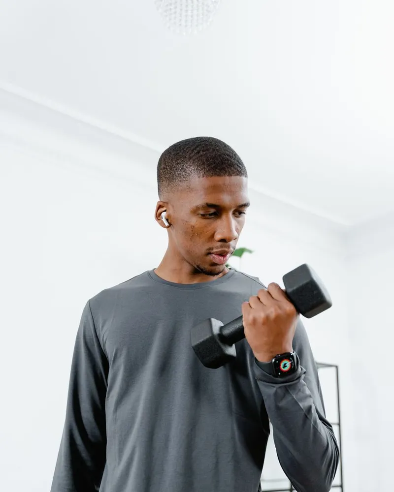 Homem fazendo rosca com halter num treino rápido na academia