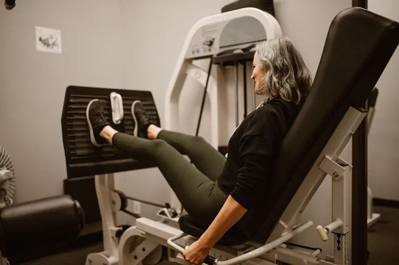 Mulher treinando na cadeira extensora da academia