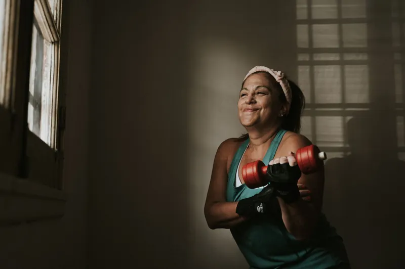 Mulher treinando com halteres em casa