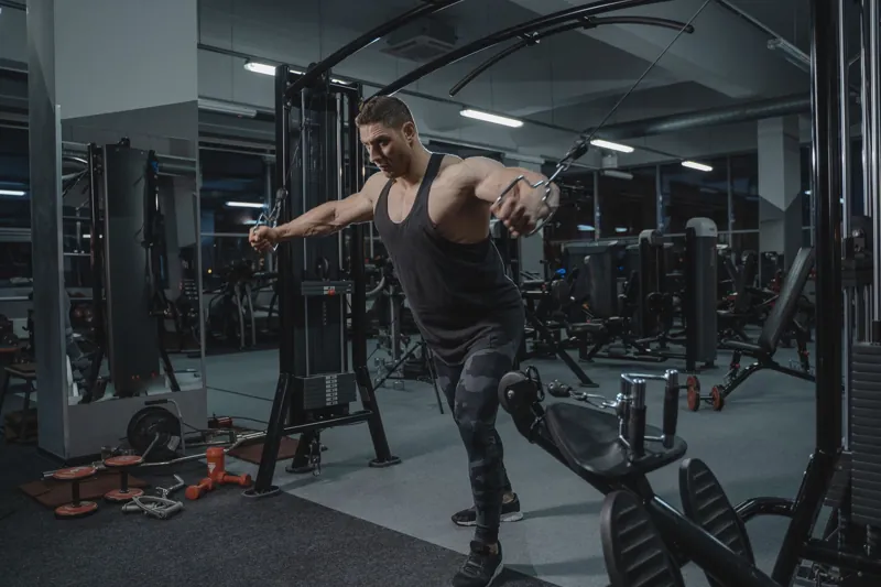 Homem treinando na polia da academia